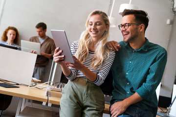 Two young businesspeople using a digital tablet while standing in a boardroom.