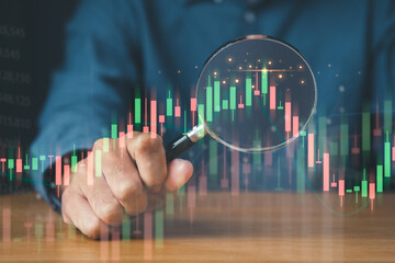 Businessman using magnifier focus on financial graph for business investment growth and money concept.