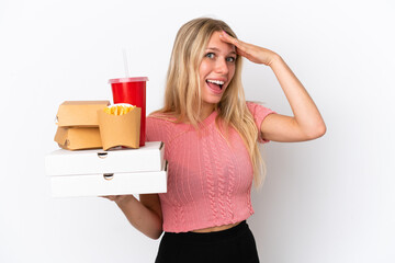 Young caucasian woman holding fat food isolated on blue background with surprise expression