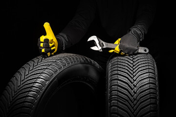 Winter car tires service and thumbs up hands of mechanic with wrench, screwdriver on black...