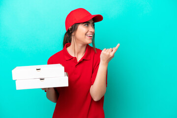 Pizza delivery woman with work uniform picking up pizza boxes isolated on blue background intending to realizes the solution while lifting a finger up