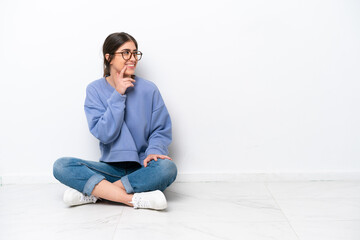 Young caucasian woman sitting on the floor isolated on white background thinking an idea while...