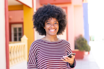 African American girl using mobile phone at outdoors smiling a lot