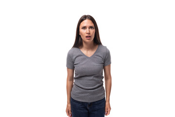 young surprised brunette promoter woman dressed in a gray t-shirt on a white background