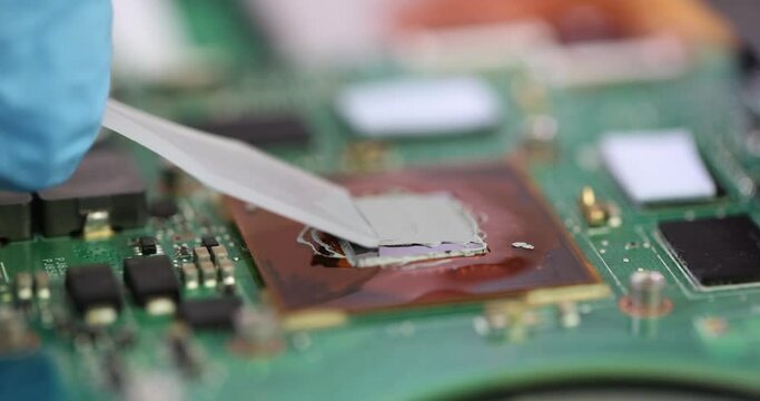 Master repairman applying thermal paste on microchip video card closeup 4k movie slow motion. Repair and maintenance of computer equipment and electronics concept