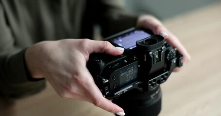Woman photographer looking at photos on black professional camera closeup 4k movie slow motion. Hobby photography concept