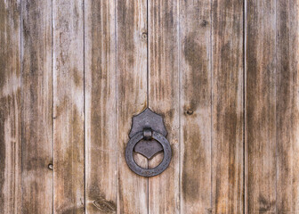 Part of a large wooden door with an iron handle and ring. Spain