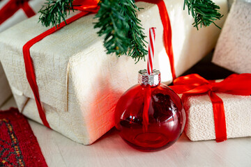 Christmas decorations. A red glass tumbler-ball  with a straw like a candy cane under a Christmas tree