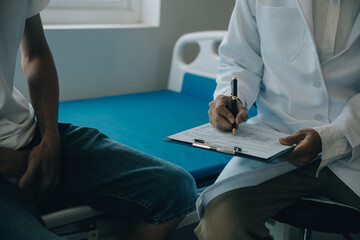 Doctor or physical therapist examines back pain and spinal area to give advice within the rehabilitation center.