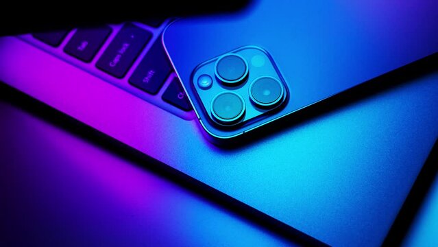 Close up of laptop and smartphone in neon light