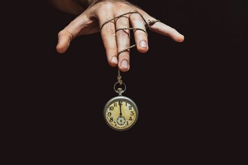 Old clock showing time under hand control for motivation or business concept