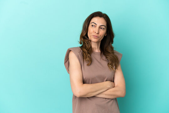Middle aged caucasian woman isolated on blue background keeping the arms crossed