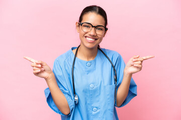 Young nurse Colombian woman isolated on pink background pointing finger to the laterals and happy