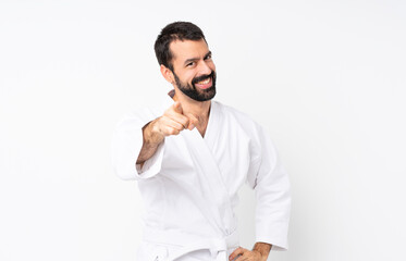Young man doing karate over isolated white background points finger at you with a confident expression