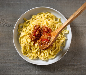 bologna sauce is added to a bowl of pasta
