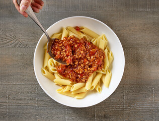 bologna sauce is added to a bowl of pasta