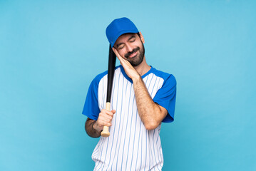Young man playing baseball over isolated blue background making sleep gesture in dorable expression