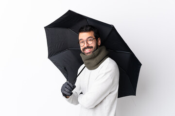 Caucasian handsome man with beard holding an umbrella over isolated white wall with arms crossed and looking forward