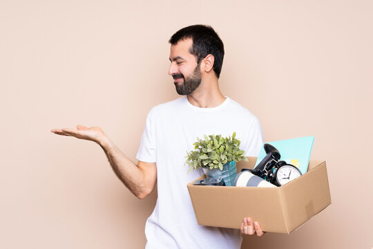 Man holding a box and moving in new home over isolated background holding copyspace with two hands