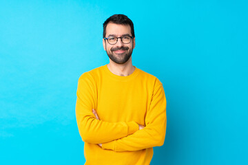 Young caucasian man over isolated blue background with glasses and happy