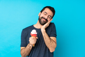 Young man with a cornet ice cream over isolated blue background making sleep gesture in dorable...