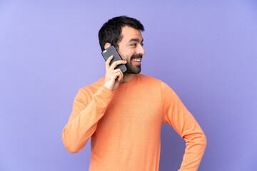 Caucasian handsome man over isolated purple background keeping a conversation with the mobile phone...
