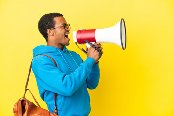 African American student man over isolated yellow background shouting through a megaphone