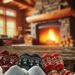 Legs with christmas socks on retro old wooden table. Empty space for your decoration. Home interior with fireplace and magic time in december. Mockup place for your decoration.Warm dark light.