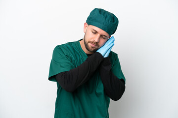 Surgeon in green uniform isolated on white background making sleep gesture in dorable expression
