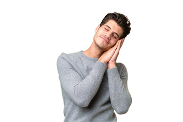 Young handsome caucasian man over isolated background making sleep gesture in dorable expression