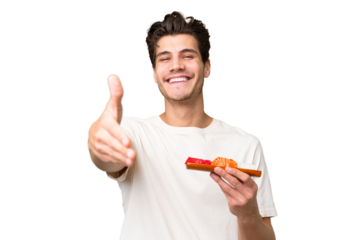 Young caucasian man holding sashimi over isolated background shaking hands for closing a good deal
