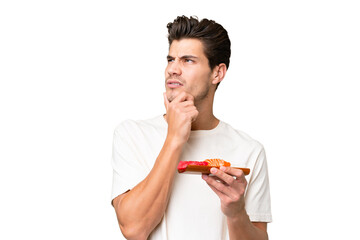 Young caucasian man holding sashimi over isolated background having doubts