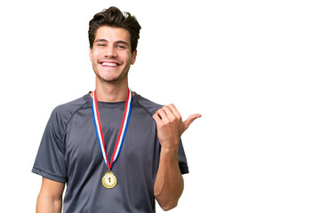 Young caucasian man with medals over isolated background pointing to the side to present a product