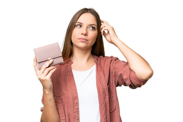Young blonde woman holding a wallet over isolated chroma key background having doubts and with...