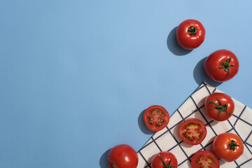 View from above of fresh tomatoes decorated on blue background with a fabric. Empty space for product promotion extracted from Tomato (Solanum lycopersicum)