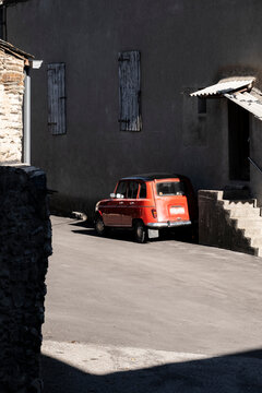 An old four-wheel drive red car on a street in a small town in the Pyrenees in France