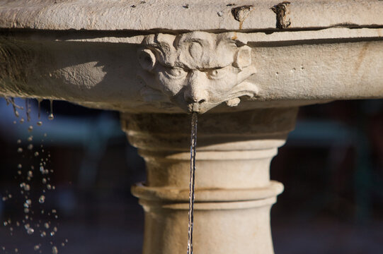 Stone fountain from which crystal clear water spurts out of a non-human head. Seville, Spain.
