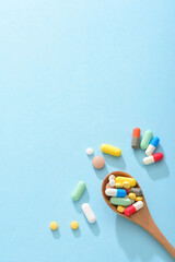A large amount of medicine and a wooden spoon filled with medicine on a blue background