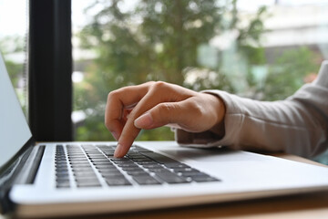 Closeup of young businesswoman typing on a laptop keyboard searching information or browsing