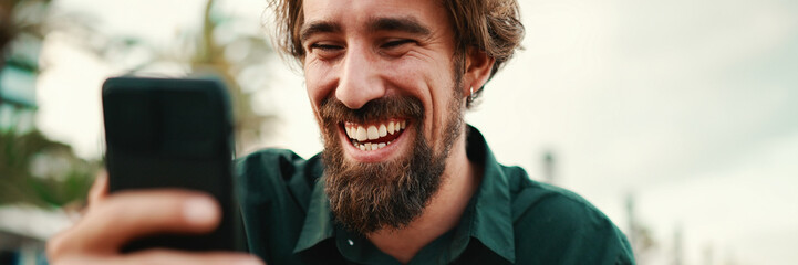 Close-up portrait of a man with a beard recording a voice message on the embankment background....