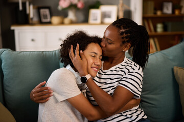 Portrait of embraced teenage boy and his mother at home