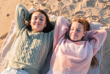 Happy young girlfriends resting on sandy beach during vacation