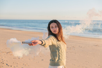 Beautiful woman holding white smoke bomb on beach - Powered by Adobe