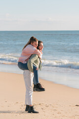 Happy female friends enjoying piggyback ride on beach