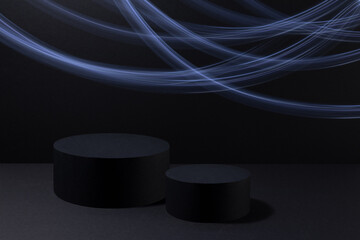 Abstract two black round podiums for cosmetic products with glowing neon blue light stripes in...