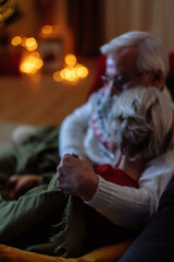 Older couple watching a tv during Christmas holidays as grandma feels sleepy