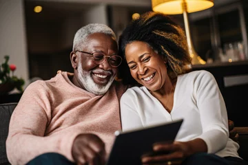 Fotobehang Scene with an elderly black couple smiling and looking at a tablet together © Creative Clicks