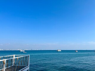 Fototapeta premium White wooden bridge and sea view on viewpoint. Seascape with passenger transport boat. Blue sea and blue sky. The calm sea. Beautiful view during trip. Travel around island. Sea wallpaper.