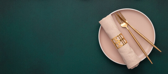 Plate with fork and knife. Mockup with empty space. Gold cutlery, dark green background. Top view....