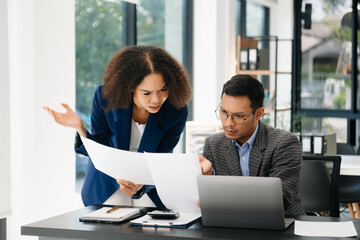 Furious two Asian businesspeople arguing strongly after making a mistake at work in office.